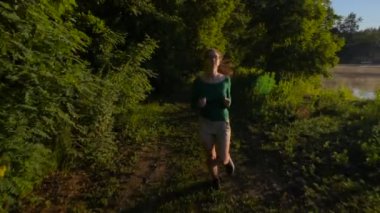 göl yakınındaki ormanda günbatımı veya gündoğumu sırasında çalışan genç sportif erkek