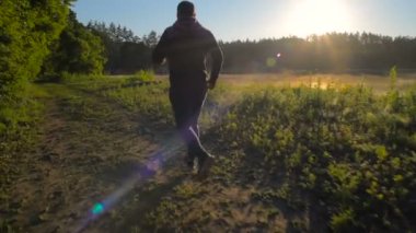 Göl kenarında günbatımı veya gündoğumu sırasında çalışan genç erkek