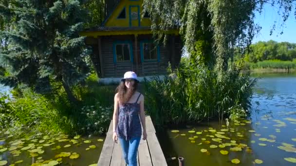 若い女性の家の近くの田園地帯で湖の上を歩いて — ストック動画