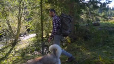 erkek ile nehir kenarında hiking sırt çantası ve Sibirya husky köpek