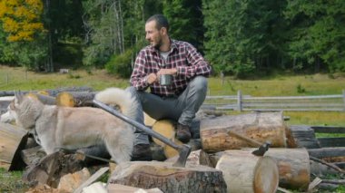 Sibirya husky köpek ile doğranmış ahşap üzerine çay içme adam