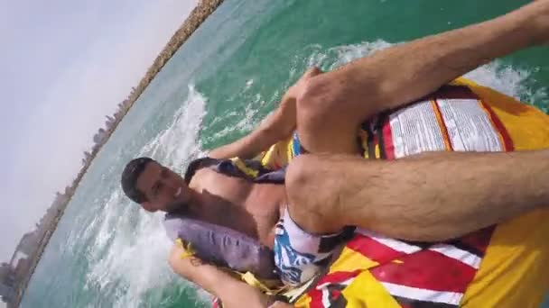 Hombre sentado en anillo inflable remolcado por un barco en el agua y grabándose con la cámara Go Pro — Vídeo de stock