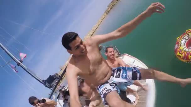 Young man filming himself thrown into the water from a boat by his friends — Stock Video