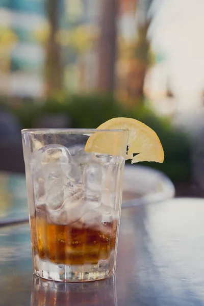 Vaso con cola, hielo y limón en una mesa exterior — Foto de Stock