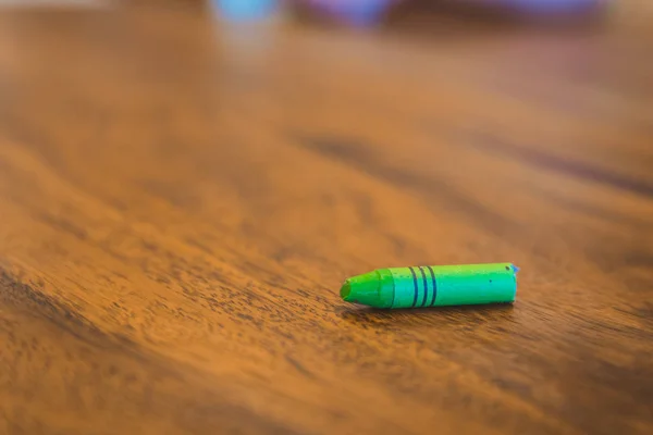 Green color pastel crayon on brown wooden table — Stock Photo, Image