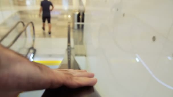Gros plan sur un homme anonyme tenant un escalator qui descend dans un centre commercial — Video