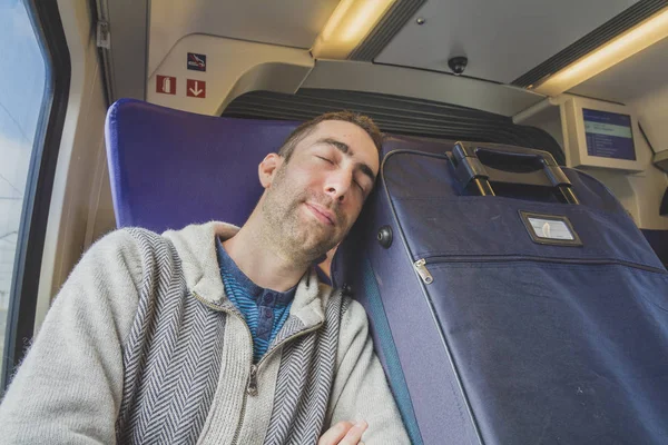 Joven viajando en un tren y dormir en la maleta azul al lado t — Foto de Stock