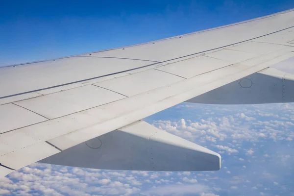 Ala de avión en el cielo y sobre el mar con nubes — Foto de Stock