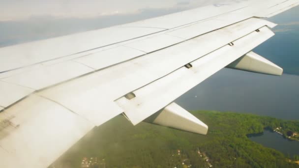 Крыло самолета во время посадки с закрылками на небе над землей — стоковое видео