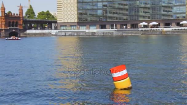 Yellow red and white steel navigational floating buoy in the blue Spree river water — Stock Video