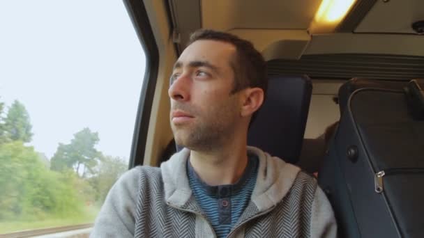 Jeune homme voyageant dans un train et regarde par la fenêtre — Video