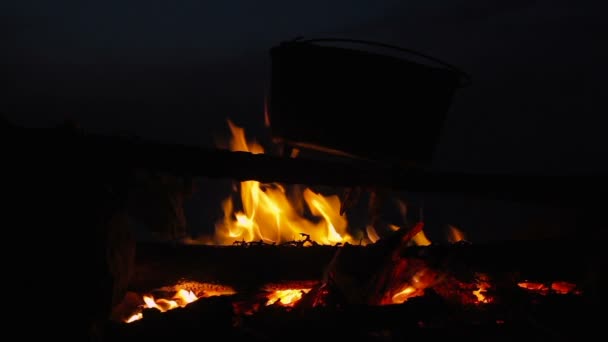 Kinotag vom Kochen im Kessel am brennenden Lagerfeuer in der Nacht — Stockvideo