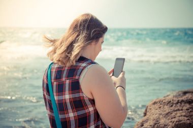 Kadın onun smartphone açık havada denize sıfır plaj kullanarak.