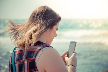 Kadın onun smartphone açık havada denize sıfır plaj kullanarak.