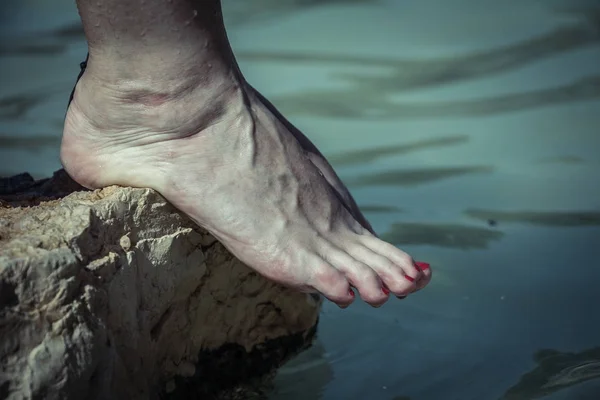 Water dripping from caucasian woman bare feet on a rock edge at the river — Stock Photo, Image