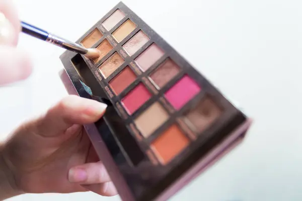 Närbild på kvinna händer som håller färgglad makeup ögonskugga palet — Stockfoto