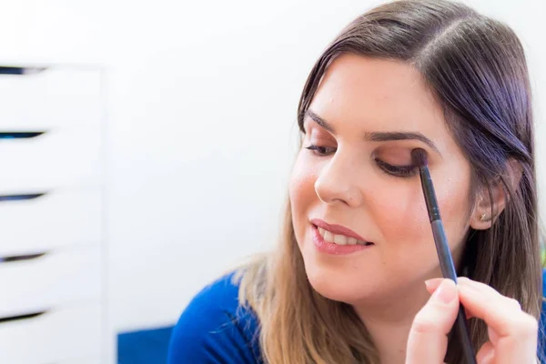 Mujer aplicando maquillaje en su dormitorio — Foto de Stock