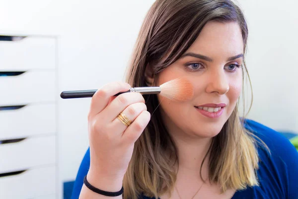 Mujer aplicando maquillaje en su dormitorio — Foto de Stock