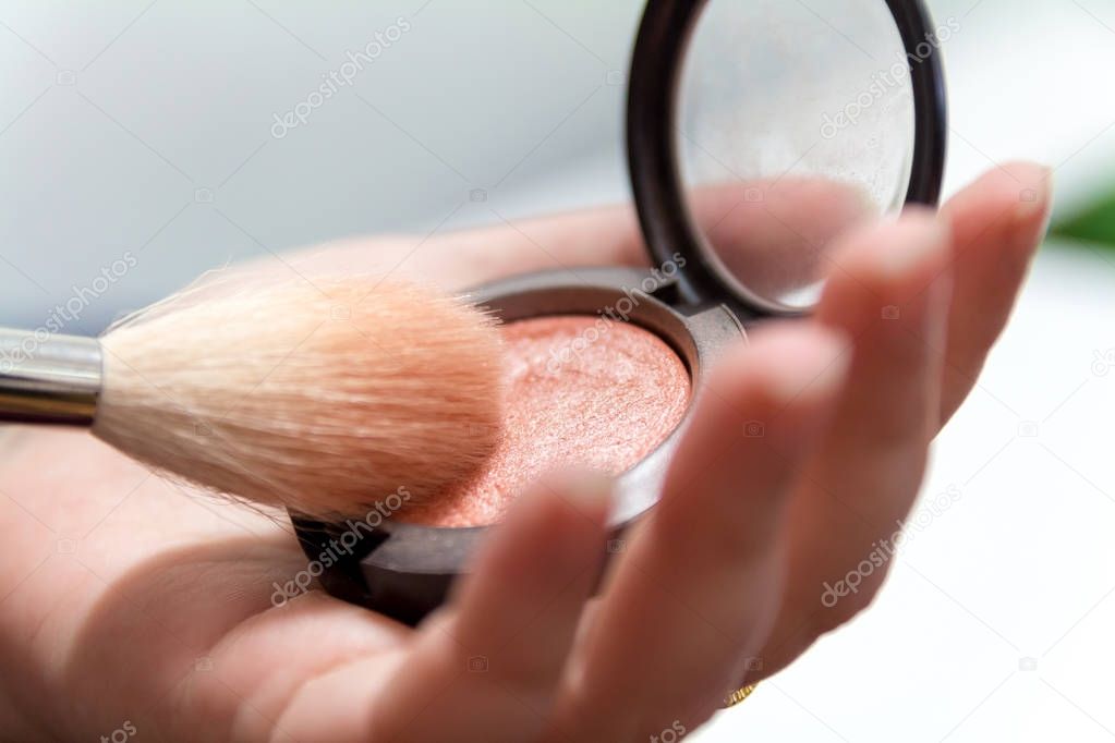 Close up of woman hands holding makeup brush and blush box