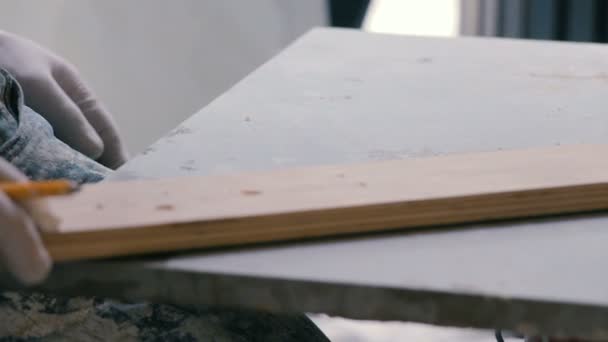 Fliesenleger misst und markiert eine Fliese mit Bleistift. Vorbereitung einer Keramikfliese für den Fußboden auf der Baustelle.