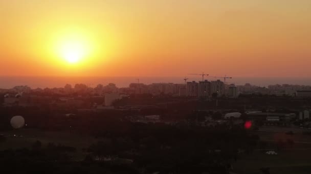 Vista aérea do horizonte de Tel Aviv ao pôr-do-sol - silhueta de edifícios, um balão de ar quente voando no céu e barcos no lago em Hayarkon Park . — Vídeo de Stock