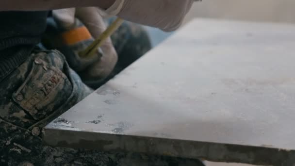 专业瓷砖工人的措施和标记一个瓷砖与铅笔。在建筑工地为地板准备瓷砖. — 图库视频影像