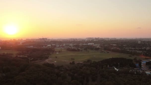 Vista aérea del horizonte de Tel Aviv al atardecer - silueta de edificios, un globo aerostático volando en el cielo y barcos en el lago en Hayarkon Park . — Vídeo de stock