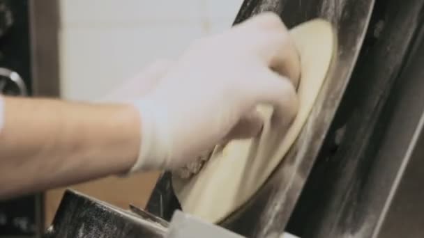Chef preparing a dough for pizza in stretching machine — Stock Video