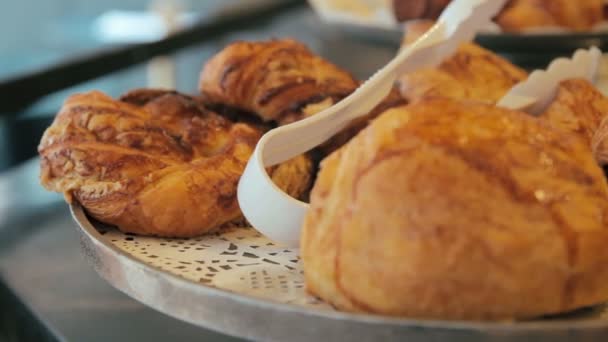 Moving panning right shot of many sweet crispy croissants and rugelach placed on a tray in a cafe or bakery shop — Stock Video