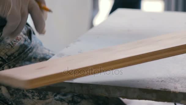 Professional tiling worker measures and marking a tile with pencil. Preparing a ceramic tile for floor at construction site. — Stock Video