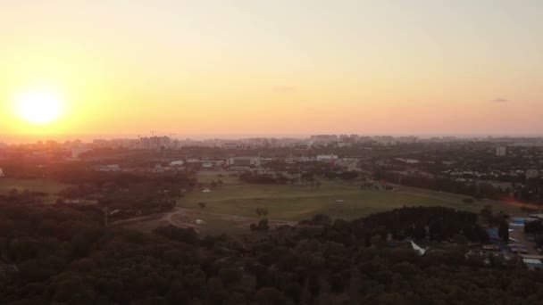 Luchtfoto van Tel Aviv skyline bij zonsondergang - silhouet van gebouwen, een hete luchtballon vliegen in de lucht en de boten in het meer in Hayarkon Park. — Stockvideo