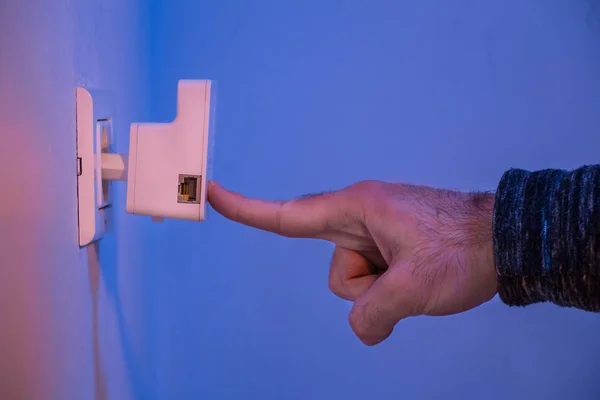 Homme appuyez avec son doigt sur le bouton WPS sur le répéteur WiFi qui i — Photo