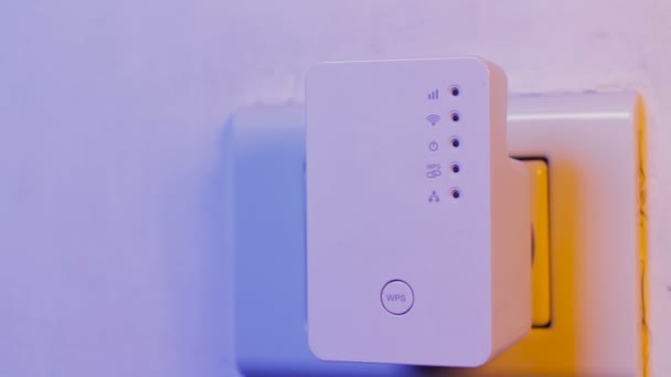 Hombre pulse con el dedo en el botón WPS en el repetidor WiFi que está en la toma de corriente en la pared. El dispositivo ayuda a extender la red inalámbrica en el hogar u oficina . — Vídeo de stock