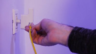 Adam, kablosuz ağ kablosunu duvardaki elektrik prizine takıyor. Cihaz, evdeki ya da ofisteki kablosuz ağı genişletmek için erişim noktası kipinde..