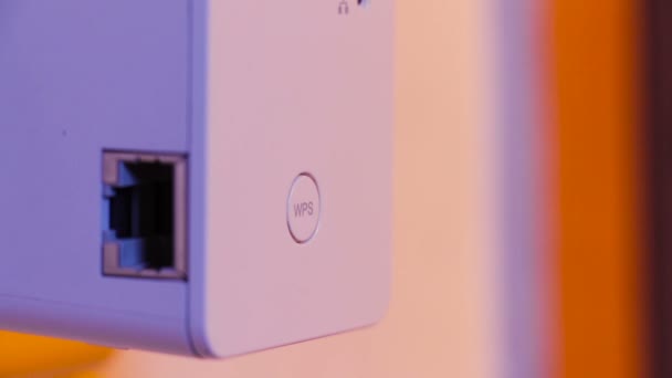 Hombre pulse con el dedo en el botón WPS en el repetidor WiFi que está en la toma de corriente en la pared. El dispositivo ayuda a extender la red inalámbrica en el hogar u oficina . — Vídeos de Stock