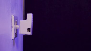 Adam, kablosuz ağ kablosunu duvardaki elektrik prizine takıyor. Cihaz, evdeki ya da ofisteki kablosuz ağı genişletmek için erişim noktası kipinde..