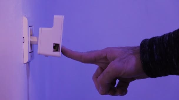 Man press with his finger on WPS button on WiFi repeater which is in electrical socket on the wall. The device help to extend wireless network in home or office. — Stock Video