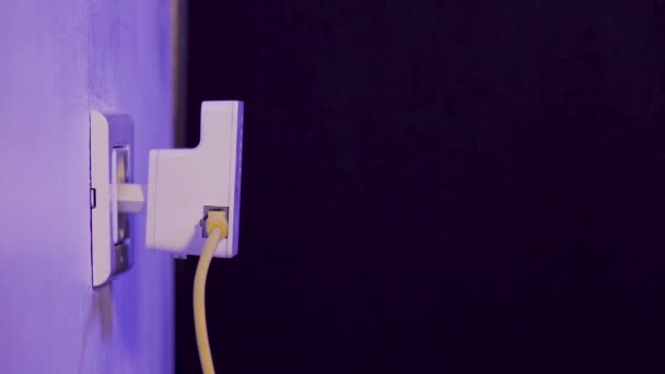 O homem desconecta o cabo ethernet do dispositivo extensor WiFi que está na tomada elétrica na parede. O dispositivo está no modo de ponto de acesso que ajuda a estender a rede sem fio em casa ou no escritório . — Vídeo de Stock