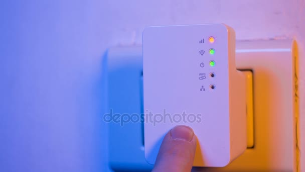 Cinemagrafo dello stato lampeggiante della connessione del segnale luci a led nel ripetitore WiFi. Primo piano dell'uomo premere con il dito sul pulsante WPS. Il dispositivo è in presa elettrica sulla parete. Aiuta ad estendere la rete wireless in casa o in ufficio . — Video Stock