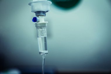 Damardan damardan serum damlatın. Hastane odasına serum damlatın. Kapat, koyu mavi ışık arkaplanı, seçici odak ve kopyalama alanı.