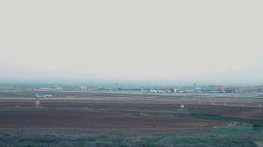 Ben Gurion Uluslararası Havaalanı 'nın öğleden sonra havadan görüntüsü. El Al Havayolları ticari uçağı kalkıyor. Uçaklar 1 ve 3 numaralı terminallerin yakınına park ediyor..