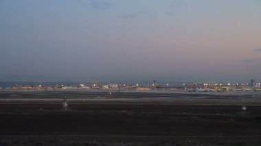 Gece Ben Gurion Uluslararası Havaalanı 'nın havadan görüntüsü. Uçaklar pistte hareket ediyor. El Al Havayolları ticari uçaklar ve 1 ve 3 numaralı terminallerin yakınındaki diğer park yerleri..