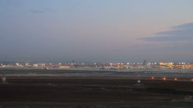 Gece Ben Gurion Uluslararası Havaalanı 'nın havadan görüntüsü. Bir uçak kalkıyor. El Al Havayolları ticari uçaklar ve 1 ve 3 numaralı terminallerin yakınındaki diğer park yerleri..