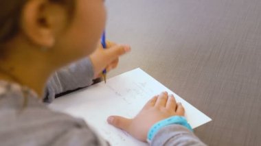 Küçük İsrailli beyaz yetenekli kız bir ilkokul sınıfında not defterine yazıyor. Egzersizi çözmeye ve cevaplarını kağıda yazmaya çalışıyor. Elleri ve bir kalemi kapalı..