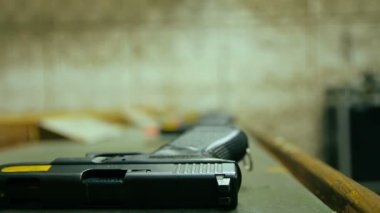 Adam 9 mm 'lik bir tabanca aldı ve atış poligonunda ateş etti. Arka planda daha fazla adam var. Kapat, seçici odaklan ve boşluğu kopyala.