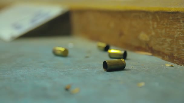 空のピストル銃弾の殻が落下し 射撃場で木製のテーブルに影響を与えます 極端なクローズアップ ぼやけた背景とコピースペースで選択的な焦点 — ストック動画