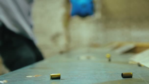 空空如也的手枪子弹落在射击场的木制桌子上 男子拍摄与9毫米枪的背景 选择性聚焦和复制空间 — 图库视频影像