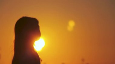 Kaygısız, tanınmayan bir kızın gölgesinin arkası egzotik bir günbatımının güzel bir manzarasının keyfini çıkarıyor. Sahilde güneşe doğru duruyor. İsrail, Tel Aviv 'de altın gün doğumu.