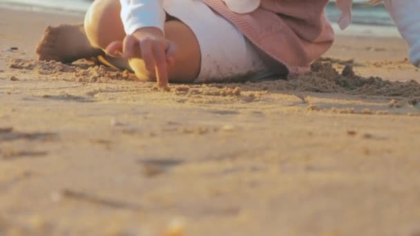 エキゾチックな夕日でぬれた砂の上にハートの形を描く無料の認識できない女の子 イスラエルのテルアビブで黄金の日の出でさわやかな海と熱帯のビーチの低角度 — ストック動画