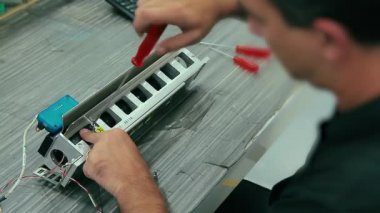 Elektrikçi sineması bir fabrikadaki makineye elektrikli ekipman monte eder. İsrail Kafkasyalı mühendis vidalarını tornavidayla sıkıyor..